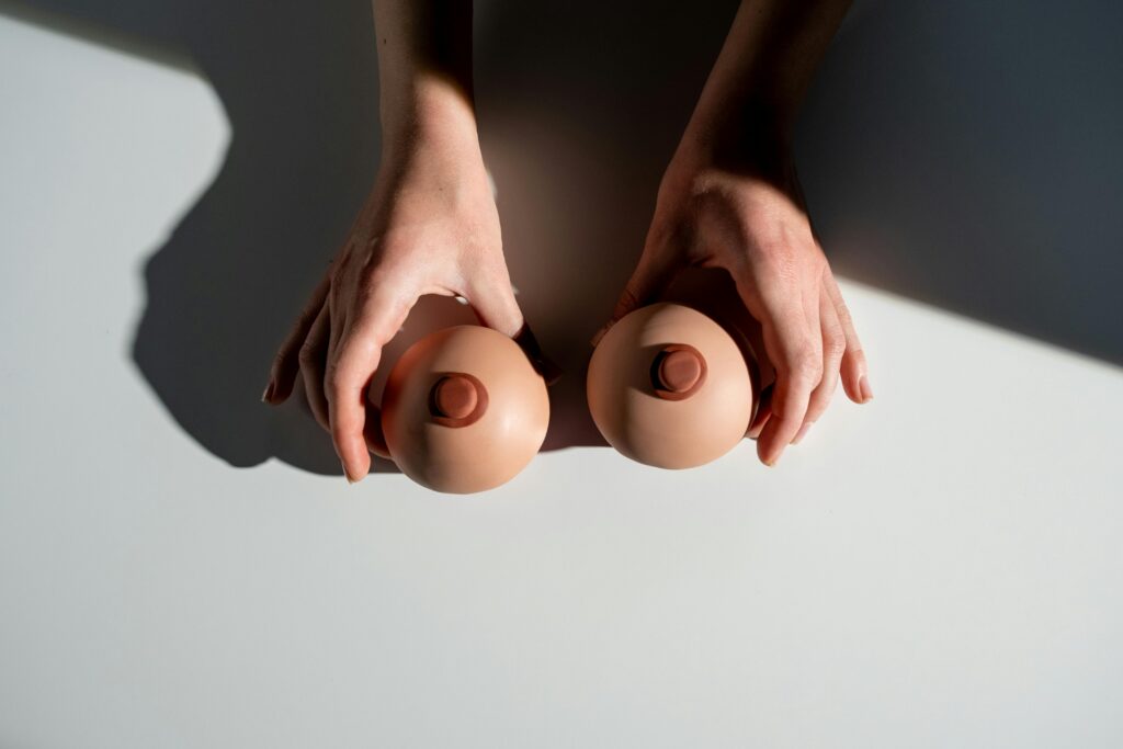 Artistic representation of breast health awareness using hands with model props under light.