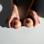 Artistic representation of breast health awareness using hands with model props under light.